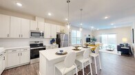 Located in Mason, Ohio, this well-appointed single-story home offers a bright and modern living experience across two bedrooms, two bathrooms, and a versatile office space. The welcoming entrance opens into a flowing open-concept layout where the kitchen, dining area, and living room connect seamlessly. The kitchen is a standout, featuring crisp white cabinetry, subway tile backsplash, stainless steel appliances, a large center island with an undermount sink, and elegant pendant lighting — all overlooking the living and dining areas. The living room is bathed in natural light from a sliding glass door and large windows, creating an airy, inviting atmosphere. Hardwood-style flooring runs throughout the main living areas, adding warmth and continuity. The generously sized primary bedroom offers a comfortable retreat with plush carpet, while the second bedroom provides additional flexibility. The dedicated office is bright and sun-drenched, with large windows that fill the space with natural light — ideal for working from home. Both bathrooms are finished with clean, contemporary fixtures. Abundant closet storage is distributed throughout the home. The attached garage provides convenient direct interior access, completing this functional and stylishly finished residence.