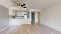 Located at 2170 S Harbor Blvd in Anaheim, CA, this two-bedroom, two-bathroom single-floor residence offers a well-organized layout designed for comfortable everyday living. Light wood-look flooring flows consistently throughout the entire space, lending a clean, cohesive aesthetic to every room.

The combined kitchen and living area forms the heart of the home. The kitchen is outfitted with stainless steel appliances — including a refrigerator, electric range, and over-the-range microwave — complemented by white cabinetry and a peninsula counter that opens toward the living room. A ceiling fan overhead keeps the space comfortable year-round. The living room benefits from a large window and a glass-paneled door that provides direct access to an outdoor patio, filling the area with natural light.

The primary bedroom is a generously sized retreat featuring mirrored sliding closet doors and a window offering outdoor views. Both bedrooms connect conveniently to the hallway, which leads to the two bathrooms. Each bathroom is finished in a crisp, clean white palette with a tub-shower combination, and one features a white vanity with stone-look countertop and chrome fixtures.

A dedicated hallway and closet complete the thoughtfully arranged floor plan, maximizing storage and circulation throughout this Anaheim residence.
