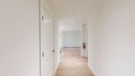 This thoughtfully designed three-bedroom, two-bathroom residence in Laurel, Maryland offers a clean, modern aesthetic highlighted by light wood flooring and crisp white walls throughout. The well-appointed kitchen serves as a central feature, showcasing white shaker cabinetry extending to the ceiling, marble-look tile backsplash, stainless steel appliances including a refrigerator, range, microwave, and dishwasher, and a large white quartz island ideal for dining or meal prep. Recessed lighting illuminates the space efficiently. The open living area extends to a private balcony through sliding glass doors, bringing in abundant natural light and outdoor views. Each bedroom is bright and well-proportioned, with large windows fitted with blinds that allow for natural light and privacy. The primary bedroom includes a dedicated closet with built-in shelving. Both bathrooms are finished consistently, featuring white subway tile tub-and-shower surrounds, white vanities with quartz countertops, brushed nickel hardware, and light wood-style flooring. A central hallway connects all rooms seamlessly. The overall ambiance is clean, bright, and move-in ready, reflecting contemporary design sensibilities suited for comfortable everyday living.