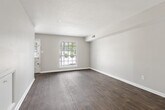 This two-story residence offers a practical and well-organized layout spread across two floors. The main level features durable wood-style flooring throughout the open living area, which is bathed in natural light from large windows fitted with blinds. The kitchen is efficiently designed with white cabinetry, ample counter space, and white appliances including a range and refrigerator. A dedicated dining area adjacent to the kitchen includes a windowed door providing additional natural light and exterior access.

Upstairs, both bedrooms are finished with soft carpeting and equipped with ceiling fans for year-round comfort. The primary bedroom offers a generous footprint with a closet, while the second bedroom also includes a closet and a window overlooking the outdoors. Each bedroom benefits from neutral wall tones that create a calm, versatile atmosphere.

The two bathrooms are clean and functional. The full bathroom features a tub-shower combination with tiled surround, a vanity with sink, and wood-style flooring, while the second bathroom is appointed with modern chrome fixtures. A dedicated closet provides additional storage. The home's straightforward design, consistent finishes, and ample natural light throughout make it a comfortable and efficient living space.
