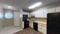 This single-floor unit offers a practical and comfortable layout across two bedrooms and two full bathrooms, with the added bonus of a sunroom. The kitchen is well-equipped with black appliances, including an electric range, over-the-range microwave, and dishwasher. Ample white cabinetry provides generous storage, while light countertops offer functional workspace. Dark hardwood-style flooring runs through the kitchen and transitions seamlessly into the living areas, complementing the neutral gray walls throughout.

The living area features a ceiling fan and connects via an arched doorway to the sunroom, which brings in additional natural light. One bedroom offers carpeted flooring, dual windows with blinds, and a ceiling fan. The second bedroom features hardwood-style flooring, multiple windows, and a walk-in closet with wire shelving. Both bathrooms are equipped with a tub/shower combination, vanity, and neutral finishes. Textured ceilings are consistent throughout, and tile flooring is present at the entryway. The overall design is clean and functional, making efficient use of the available space.
