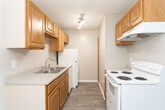 Located at 3820 Mizell Rd in Greensboro, NC, this single-floor unit offers a straightforward, functional layout with a neutral color palette throughout. The flooring transitions between wood-look planks in the main living areas and soft carpeting in the bedrooms, creating a clear distinction between shared and private spaces.

The living area is generously proportioned, featuring a sliding glass door that invites natural light and provides outdoor access. An adjacent entry area also features wood-look flooring and offers a defined transition point into the main living space.

The kitchen follows a galley-style configuration, lined on both sides with warm-toned oak cabinetry providing ample storage. It is equipped with white appliances including an electric range, refrigerator, and dishwasher, along with a stainless steel sink and light countertops. A pendant light fixture adds a subtle decorative element above the dining area.

The bedrooms are carpeted and finished with neutral walls. Each features a closet with a hanging rod, and windows allow natural light to filter in. Textured ceilings are consistent throughout the unit, and white trim and baseboards provide clean visual definition across all rooms.