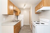 Located at 3820 Mizell Rd in Greensboro, NC, this single-floor unit offers a straightforward, functional layout with a neutral color palette throughout. The flooring transitions between wood-look planks in the main living areas and soft carpeting in the bedrooms, creating a clear distinction between shared and private spaces.

The living area is generously proportioned, featuring a sliding glass door that invites natural light and provides outdoor access. An adjacent entry area also features wood-look flooring and offers a defined transition point into the main living space.

The kitchen follows a galley-style configuration, lined on both sides with warm-toned oak cabinetry providing ample storage. It is equipped with white appliances including an electric range, refrigerator, and dishwasher, along with a stainless steel sink and light countertops. A pendant light fixture adds a subtle decorative element above the dining area.

The bedrooms are carpeted and finished with neutral walls. Each features a closet with a hanging rod, and windows allow natural light to filter in. Textured ceilings are consistent throughout the unit, and white trim and baseboards provide clean visual definition across all rooms.
