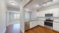 Located at 12000 Sweet Pl in Charleston, SC, this single-floor 1-bedroom, 1-bathroom residence offers a thoughtfully designed layout with quality finishes throughout. The kitchen is a standout feature, boasting white shaker cabinetry, granite countertops, a double-basin sink, pendant and track lighting, and a full suite of stainless steel appliances including a range, microwave, dishwasher, and refrigerator. Warm hardwood flooring runs through the kitchen and living areas, complemented by crown molding that adds a refined architectural touch. The living room is bright and open, benefiting from natural light and a ceiling fan overhead. The generously sized bedroom features plush carpeting, a ceiling fan, crown molding, and a bank of windows that invite ample natural light and outdoor views. A dedicated walk-in closet provides multi-tier wire shelving for organized storage. The bathroom is clean and functional, offering a granite-topped vanity, a full tub-shower combination, and hardwood-style flooring. Neutral tones and consistent finishes create a cohesive, move-in-ready ambiance throughout the entire residence.