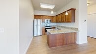 This well-appointed 2-bedroom, 1-bathroom home in Lehi, Utah offers a thoughtfully designed single-floor layout. The bright and open living room serves as the heart of the home, featuring light hardwood-style flooring, vaulted ceilings, a ceiling fan, and a classic white-framed fireplace. Large windows allow generous natural light to fill the space and offer views of the surrounding neighborhood.

The kitchen is a functional highlight, showcasing warm wood cabinetry, granite countertops, a peninsula with a built-in sink, stainless steel appliances including a refrigerator, range, and microwave, and pendant lighting above — all complemented by soaring ceilings that add to the sense of openness.

Both bedrooms feature plush carpeting and large corner windows that bring in ample natural light and outdoor views. The primary bedroom includes a spacious walk-in closet with built-in shelving and hanging rods, while the secondary bedroom offers a double-door closet for additional storage.

The full bathroom is neatly finished with wood cabinetry, granite countertops, a tub-shower combination with tiled surround, and hardwood-style flooring. A dedicated laundry room with side-by-side washer and dryer and overhead shelving rounds out this practical and comfortable home.
