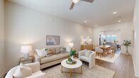 Located in North Charleston, SC, this two-story, 2-bedroom, 3-bathroom home offers a well-designed layout spread across two comfortable floors. The main level opens into a bright, airy living room featuring hardwood-style flooring, elevated ceilings, a ceiling fan, and large windows that flood the space with natural light. The living area flows seamlessly into a dedicated dining room, distinguished by its marble-style tile flooring, a round mirror, and direct sightlines into the kitchen. The kitchen is a standout feature, boasting gray shaker cabinetry, a generous center island with white quartz countertops, stainless steel appliances including a dishwasher, pendant lighting, and abundant natural light from multiple windows. A hallway and staircase connect to the upper level, where two bedrooms and additional bathrooms are located. The spacious primary bedroom features wide windows offering outdoor views, a ceiling fan, and wood-style flooring. The bathrooms are finished with gray vanity cabinetry, white quartz countertops, and glass-enclosed showers. Throughout the home, a neutral, light-toned palette creates a cohesive and calming ambiance that is both modern and inviting.