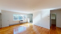 This single-floor residence at Soundview Gardens in Port Washington North, NY offers a clean, well-maintained layout designed for comfortable everyday living. The open living area is a standout feature, showcasing gleaming hardwood floors that reflect abundant natural light streaming through a large picture window. Baseboard heating and a wall-mounted AC unit ensure year-round comfort, while crisp white walls provide a bright, neutral backdrop throughout.

The kitchen has been thoughtfully updated with dark espresso-toned cabinetry, light quartz countertops, a mosaic tile backsplash, and recessed lighting. White appliances including a gas range, over-the-range microwave, refrigerator, and dishwasher are all included. Light-toned tile flooring complements the cabinetry for a cohesive, modern aesthetic.

The bedroom offers a comfortable amount of space, hardwood flooring, a built-in closet, and a window that brings in natural light. The bathroom features classic white subway tile surrounding a tub and shower combination with sliding glass doors, a vanity with storage, and tile flooring, creating a clean, timeless finish throughout.