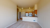 Located at 5207 West Hildebrand Boulevard in Kennewick, Washington, this single-floor unit offers a well-designed, open-concept layout that maximizes both functionality and comfort. The kitchen serves as a central hub of the home, featuring warm honey-toned wood cabinetry, dark laminate countertops, a peninsula with an integrated sink, and white appliances including a refrigerator, electric range, microwave, and dishwasher. Light hardwood flooring anchors the kitchen and entry areas, creating a clean and inviting transition into the home. The living area flows seamlessly from the kitchen, bathed in natural light from large sliding glass doors that open to an outdoor balcony, providing pleasant exterior views. Two generously sized bedrooms are finished with soft wall-to-wall carpeting and feature large windows that bring in ample daylight. One bedroom includes a wall-mounted HVAC unit, while the other benefits from a baseboard heater. The full bathroom is appointed with hardwood flooring, a wood-toned vanity with stone-look countertop, a mirrored medicine cabinet, and a full tub-shower combination equipped with safety grab bars. Warm neutral tones and vaulted ceiling heights in select areas contribute to an airy, spacious ambiance throughout the unit.