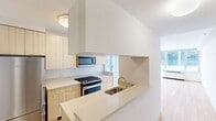 This contemporary 640 square foot apartment, located at 601 West 57th Street in New York City, offers a thoughtful blend of style and functionality. The one-bedroom unit is situated on a single floor, maximizing space efficiency. The primary bedroom, measuring 150 square feet, provides ample room for rest and relaxation.

The open-concept living area seamlessly integrates the kitchen and living room, creating a spacious feel. Large windows flood the space with natural light and offer urban views, enhancing the sense of openness. The apartment features beautiful hardwood floors throughout, adding warmth and elegance to the modern design.

The kitchen is equipped with sleek, light-colored cabinetry, stainless steel appliances, and a gas range, catering to culinary enthusiasts. The bathroom boasts a clean, contemporary design with a large mirror and ample counter space. Built-in closets in the bedroom and hallway provide generous storage options.

Climate control is ensured by an efficient PTAC unit, maintaining comfort year-round. The neutral color palette and minimalist design create a canvas for personal expression, allowing residents to easily customize their living space. This apartment offers a perfect balance of comfort and style in the heart of Midtown Manhattan.