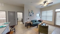 This well-designed single-floor unit at 115 Dayton St in Hamilton, Ohio offers a comfortable and modern living experience. The open-concept living area is bright and inviting, featuring light wood-style flooring, neutral walls, and a ceiling fan that enhances air circulation. Large windows with blinds allow ample natural light to fill the space, creating a warm and welcoming ambiance. Contemporary abstract artwork adorns the walls, adding a stylish touch throughout.

The kitchen is a standout feature, boasting rich dark cabinetry, granite countertops, and stainless steel appliances including a range, microwave, and refrigerator. A generously sized center island with seating provides an ideal space for casual dining or entertaining, complemented by pendant lighting overhead.

The bedroom is a serene retreat with plush carpeting, a ceiling fan, and a large window that invites natural light. It connects directly to a spacious en-suite bathroom, which features dual sinks set in dark cabinetry with granite countertops, a large mirror, and a glass-enclosed walk-in shower. Light wood-style flooring ties the bathroom together with the rest of the unit.

Additional storage space is visible throughout, and the layout flows seamlessly from room to room, offering both functionality and comfort in a clean, contemporary setting.