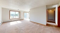 Located at 2609 #302 in Sioux Falls, South Dakota, this two-bedroom, one-bathroom unit offers a functional and comfortable single-floor layout. The living room is a welcoming, open space with large windows and a sliding glass door that invite abundant natural light and outdoor views, complemented by neutral carpeting and baseboard heating. The galley-style kitchen features warm oak cabinetry, light countertops, tile flooring, and white appliances including a refrigerator, electric range, microwave, and dishwasher, all beneath a classic overhead light fixture. The spacious primary bedroom provides a generous footprint with two side-by-side oak-trimmed closets, offering excellent storage capacity. The second bedroom is well-proportioned with a large window overlooking mature trees, carpeted floors, and baseboard heating. The full bathroom includes a tub/shower combination with clean white fixtures and oak overhead cabinetry. A dedicated laundry area accommodates full-sized washer and dryer units with overhead shelving for added convenience. Warm oak trim and wood-toned doors are consistent throughout, providing a cohesive and classic aesthetic across the entire unit.