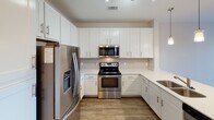 Located at 151 E Blount Ave in Knoxville, Tennessee, this well-appointed single-floor residence offers a thoughtfully designed open-concept layout. The kitchen serves as a centerpiece of the living space, boasting white shaker cabinetry with ample storage, a classic subway tile backsplash, and a full suite of stainless steel appliances including a French door refrigerator, electric range, and over-the-range microwave. A kitchen island with a double sink and pendant lighting above adds both functionality and style, flowing seamlessly into the living area. The living room features wood-style plank flooring, a ceiling fan, and a set of French doors that open to a private balcony, filling the space with natural light and offering pleasant outdoor views. The bedroom is generously sized, finished with plush carpet, a ceiling fan, and a large window that continues the theme of natural light throughout. The bathroom features a wide vanity with white cabinetry, a well-lit mirror, and a tub-shower combination. Directly accessible from the bathroom, a spacious walk-in closet with wire shelving provides excellent organizational capacity. Track lighting, recessed fixtures, and consistent wood-style flooring throughout the main areas complete the clean, contemporary aesthetic of this Knoxville residence.