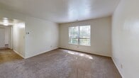 Located at 401 Rivers Post Ct in Virginia Beach, Virginia, this single-floor, three-bedroom, two-bathroom home offers a practical and well-organized layout. The living room is a bright, open space featuring neutral carpet flooring, light-toned walls, and a pass-through window connecting it to the kitchen, creating an open sightline between the two areas. Natural light fills the room, contributing to a clean and airy atmosphere.

The galley-style kitchen is efficiently designed with warm wood cabinetry, dark granite-style countertops, and tile flooring. It includes ample upper and lower cabinet storage and full appliances, including a range, over-the-range microwave, and refrigerator.

The three bedrooms are carpeted throughout and finished with neutral walls. The primary bedroom is the most spacious, featuring two six-panel closet doors and access to an adjacent room. The secondary bedrooms each include windows that invite natural light and views of surrounding greenery, with closet access in each.

Both bathrooms are finished with tile flooring and warm wood vanities. The full bathroom includes a tub-shower combination with a large mirror, while the second bathroom offers a vanity with additional utility. A hallway connects the bedroom wing to the main living areas, completing this straightforward and functional single-level home.