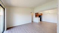 Located at 801 E Alosta Ave in Azusa, California, this single-floor residence offers three bedrooms and two bathrooms within a thoughtfully arranged floor plan. The kitchen is efficiently designed in a U-shaped layout, featuring warm medium-toned wood cabinetry, granite-style countertops, black appliances including a full-size refrigerator, range, and microwave, complemented by light wood-style flooring and a tray ceiling with flush lighting. A breakfast bar peninsula connects the kitchen to the adjacent living area, which is finished with the same light flooring and pendant lighting overhead. Each of the three bedrooms is carpeted in neutral tones, offering a comfortable feel. The primary bedroom provides generous space, while secondary bedrooms benefit from large windows with vertical blinds that invite natural light and outdoor views. One bedroom features mirrored sliding closet doors. The two bathrooms are clean and functional — one includes a full tub/shower combo with white tile surround, while the other features a wood-cabinet vanity with granite-style countertop, large mirror, and a bright window offering natural light. A connecting hallway ties the layout together seamlessly.
