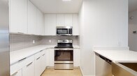 Located in the heart of Uptown Charlotte at 425 W Fifth St, this single-floor residence delivers a clean, contemporary aesthetic throughout. Light-toned hardwood flooring flows seamlessly from room to room, complementing the bright white walls and creating a cohesive, modern atmosphere.

The kitchen is thoughtfully designed with flat-front white cabinetry extending to the ceiling for ample storage, light quartz countertops, a gray subway tile backsplash, and a full suite of stainless steel appliances including a range, over-the-range microwave, and dishwasher.

The living and bedroom areas are generously proportioned, each benefiting from large windows fitted with horizontal blinds that frame views of the surrounding Charlotte skyline. The rooms are bathed in natural light, enhancing the open and airy feel of the space.

The bathroom is notably spacious and well-appointed, featuring an extended white vanity with dual sinks, quartz countertops, sleek chrome hardware, and a large mirror with overhead lighting. The layout offers both functionality and a refined, spa-like quality.

Throughout the residence, the consistent use of white tones, modern fixtures, and light wood flooring creates a polished, move-in-ready environment well-suited to urban living in downtown Charlotte.