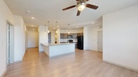 This single-floor residence offers a thoughtfully designed layout with three bedrooms, two bathrooms, and three closets. The open-concept kitchen and living area serves as the heart of the home, featuring light wood-style flooring, recessed lighting, and a ceiling fan. The kitchen is equipped with dark cabinetry, black appliances, a subway tile backsplash, and a central island topped with granite countertops and pendant lighting — ideal for both cooking and casual dining.

The hallway connects the living spaces to the private quarters, lined with panel-style doors and recessed ceiling lights that maintain a clean, modern aesthetic. The primary bedroom offers a generous footprint with a ceiling fan, large window with natural light, and wood-style flooring. The two additional bedrooms feature plush carpet, ceiling fans, and oversized windows that invite plenty of natural light and exterior views.

Both bathrooms are finished with granite-topped dark vanities and light wood-style flooring. The primary bath includes a glass-enclosed shower, while the second bath features a full soaking tub. Three closets provide ample storage throughout the residence. Clean lines, neutral tones, and consistent modern finishes give the space a cohesive and comfortable feel.