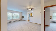 Located on Douglas Avenue in Racine, Wisconsin, this single-floor, two-bedroom, one-bathroom residence offers a practical and comfortable layout. The open-concept kitchen and living room serve as the heart of the home, where warm honey-toned cabinetry and a breakfast bar transition seamlessly into the carpeted living area. A ceiling fan overhead and large windows overlooking lush greenery fill the space with natural light and a relaxed ambiance, while a baseboard heating system and wall-mounted A/C unit ensure year-round comfort. Both bedrooms are carpeted and well-proportioned, each equipped with a ceiling fan and a generously sized closet. The primary bedroom offers a particularly spacious feel, with a large window that frames outdoor views. Two hallways connect the rooms efficiently, complemented by a total of four closets throughout the unit for ample storage. The dedicated laundry room features in-unit washer and dryer hookups and light hardwood-style flooring, adding everyday convenience. The bathroom includes tile-style flooring and direct access to the living areas. A private patio extends the living space outdoors, rounding out this well-appointed and functional home.