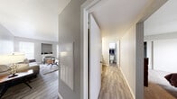 This single-floor residence offers a thoughtfully organized layout that balances comfort and functionality. The living room serves as the central gathering space, featuring wood-look plank flooring, neutral gray walls, and a built-in niche ideal for display or storage. Natural light filters in through blinds-covered windows, creating a bright and welcoming ambiance. Adjacent to the living area, the dining space is anchored by an elegant chandelier and features a sliding barn-style door that opens to an outdoor patio, seamlessly connecting indoor and outdoor living. The galley-style kitchen is efficiently designed with ample white shaker cabinetry, dark granite-style countertops, a double-basin stainless steel sink, and black appliances including a range and refrigerator, all set atop wood-look plank flooring. The bedrooms offer plush carpeting, ceiling fans with lighting, generous windows with blinds, and sliding closet doors, providing a calm and restful retreat. The bathroom features white cabinetry, a dark countertop vanity with a large mirror, and a separate water closet. A central hallway connects all areas of the home, with convenient HVAC access panels integrated into the corridor walls. The overall aesthetic is clean, modern, and move-in ready.