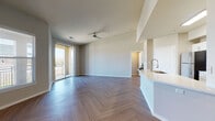 This well-designed single-floor residence offers a bright and cohesive living experience highlighted by consistent herringbone-patterned flooring throughout every room. The entryway welcomes you with clean lines and recessed lighting, setting the tone for the rest of the space.

The open-concept living area is spacious and airy, bathed in natural light from large sliding glass doors that lead to a private balcony with outdoor views. A ceiling fan adds a functional touch to the generous living space, which flows seamlessly into the kitchen.

The kitchen is outfitted with white shaker-style cabinetry, light quartz countertops, a white subway tile backsplash, and a full suite of stainless steel appliances, including a refrigerator, range, and built-in microwave. A peninsula with a sink provides additional workspace and casual dining potential.

The bedroom is comfortably sized, featuring a ceiling fan, a large window with blinds for natural light and privacy, and direct access to a spacious walk-in closet equipped with multi-level wire shelving for ample storage.

The bathroom is clean and functional, featuring a white vanity with upper cabinetry, a tiled soaking tub and shower combination, and the same herringbone flooring found throughout the residence. The neutral color palette and brushed nickel hardware tie the entire space together cohesively.
