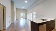 This thoughtfully designed single-floor unit offers a clean, contemporary aesthetic throughout, with light-toned luxury vinyl plank flooring and neutral walls creating a bright, cohesive atmosphere. The open-concept layout connects the kitchen and living area seamlessly. The kitchen is well-equipped with a full suite of stainless steel appliances — including a refrigerator, electric range, and built-in microwave — complemented by white cabinetry, light countertops, and a central island with a sink and integrated dishwasher. Track lighting overhead adds a modern touch to the kitchen space. The spacious living area receives natural light through a sliding glass door that opens to a private balcony. A generously sized bedroom features light-filled proportions, light vinyl flooring, and direct access to a large walk-in closet with wire shelving for ample storage. The bathroom is finished with a wide vanity, dark countertop, undermount sink, and brushed nickel hardware. A dedicated laundry closet houses a stacked Whirlpool washer and dryer, adding everyday convenience. The unit presents a move-in-ready, modern living environment with well-considered finishes and a functional floor plan throughout.