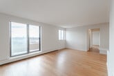 Located at 82 Millside Drive in Milton, Ontario, this well-appointed two-bedroom, one-bathroom unit offers a functional and comfortable layout across a single floor. Warm hardwood flooring flows consistently throughout the space, complementing the clean, neutral palette of white walls and modern finishes.

The kitchen is a standout feature, fitted with crisp white cabinetry, stone-finish countertops, stainless steel appliances — including a refrigerator, stove, and built-in microwave — and recessed lighting overhead. A peninsula counter connects the kitchen to the open-concept dining and living area, which is bathed in natural light and provides direct access to the private balcony. The balcony, enclosed with a brick surround, offers views of the surrounding Milton cityscape.

The primary bedroom is generously sized and benefits from large sliding windows that frame outdoor views and allow ample natural light. The second bedroom also features a window with natural light and baseboard heating. Both rooms maintain the consistent hardwood flooring found throughout the unit. A dedicated closet and hallway provide practical storage solutions.

The bathroom includes a full soaker tub with a shower combo, finished with white subway tile surround — clean and functional in design. Overall, the unit presents a bright, modern aesthetic suited for comfortable urban living in Milton.