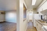 Located at 10623 E Exposition Ave in Aurora, CO, this one-bedroom, one-bathroom unit offers a practical and functional single-floor layout. The living room is an open, well-proportioned space featuring wood-style plank flooring, neutral gray walls, a wall-mounted AC unit, and a baseboard heating system. A large window allows natural light to fill the room while providing views of the surrounding area. A pass-through counter connects the living area to the galley-style kitchen, which is outfitted with white cabinetry, white appliances including a coil-top range and refrigerator, a sink, and a skylight-style ceiling fixture that brightens the narrow workspace. A hallway connects the main living areas to the private spaces, leading to the generously sized bedroom. The bedroom features soft carpet flooring, neutral tones, and a double-door closet offering ample storage. A baseboard heater and window round out the room. The bathroom includes a full-size soaking tub with tile surround, a window for natural ventilation, and clean white finishes throughout. The overall aesthetic is clean, neutral, and move-in ready.