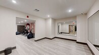 Located at 130 W Girard Ave in Philadelphia's vibrant Northern Liberties neighborhood, this fitness center offers a thoughtfully designed, two-zone workout facility spanning a generously sized single floor. The space is finished with light wood-look luxury vinyl plank flooring, neutral-toned walls, and recessed lighting throughout, creating a clean, modern aesthetic that feels both inviting and functional.

The cardio zone is the larger of the two areas and features multiple treadmills, elliptical machines, a stair climber, and a stationary bike, including an interactive cycling bike. A bold, contemporary mural with arched geometric shapes in warm terracotta and blush tones serves as a striking accent wall, adding visual energy to the space. A wall-mounted mirror at one end amplifies the sense of openness.

The strength training zone is a dedicated room equipped with a power rack, adjustable weight benches, a full set of dumbbells on tiered racks, and a cable machine. Floor-to-ceiling mirrors line two walls, allowing users to monitor their form effectively.

Adjacent to the main workout areas is a flexible open studio room featuring large wall mirrors, ideal for stretching, yoga, or group fitness activities. A water dispenser is conveniently located within the facility. Double glass entry doors with an accessible entrance complete this well-appointed fitness amenity.
