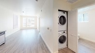 Located at 3050 Mission Inn Ave in Riverside, California, this single-floor unit offers a clean, modern aesthetic throughout. The open-concept living and kitchen area is anchored by durable wood-look flooring and large windows dressed with vertical blinds, allowing abundant natural light to fill the space. The kitchen is outfitted with sleek grey flat-panel cabinetry extending to the ceiling, dark quartz-style countertops, and a full suite of stainless steel appliances including a range, built-in microwave, and dishwasher — providing both style and functionality. The living area flows seamlessly from the kitchen, offering a bright and versatile layout. The bedrooms feature plush grey carpeting and generous closet space with sliding doors. Two bathrooms serve the unit: one includes a tub/shower combo with chrome fixtures and a grey vanity with dark countertop, while the second is a well-appointed bathroom with a window for natural ventilation, a matching grey vanity, and grab bars for accessibility. A dedicated in-unit laundry closet houses a stacked washer and dryer, adding everyday convenience. The unit's crisp white walls, consistent finishes, and thoughtful layout make it a functional and contemporary living space in the heart of Riverside.