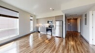 Located at 2001 Washington St in Boston's vibrant Roxbury neighborhood, this modern single-floor residence offers a thoughtfully designed layout with contemporary finishes throughout. Rich hardwood-style flooring flows seamlessly across all living areas, complementing the clean, neutral color palette that defines the space.

The open-concept kitchen is a standout feature, outfitted with full stainless steel appliances including a refrigerator, range, built-in microwave, and dishwasher. Light wood upper cabinetry pairs with sleek grey lower cabinets, accented by a bright white tile backsplash that adds a crisp, modern touch.

The bedrooms are generously proportioned, with large windows fitted with roller blinds that frame impressive views of the Boston skyline and surrounding greenery, flooding the rooms with natural light. One bedroom includes a walk-in closet for added storage.

Two well-appointed bathrooms serve the residence. The full bathroom features a soaking tub with an overhead shower, a floating vanity, and a medicine cabinet mirror. The second bathroom offers a glass-enclosed walk-in shower with a decorative tile base, a floating vanity, and matching mirror — both finished with coordinating hardwood-style flooring.

The overall ambiance is clean, bright, and contemporary, making this a well-equipped residence in one of Boston's most connected neighborhoods.
