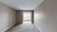 Located at 937 Trellises Dr in Florence, Kentucky, this single-floor unit offers a practical and well-organized layout with a comfortable, neutral aesthetic. The living area features plush wall-to-wall carpeting, warm taupe-toned walls, and clean white trim and baseboards. A front entryway with tile flooring transitions seamlessly into the carpeted main living space, which benefits from natural light streaming through a large window. A ceiling fan overhead adds to the room's functionality.

The kitchen is a functional highlight of the unit, designed in an open-concept style that overlooks the living area. It is equipped with honey-toned oak cabinetry, dark granite-style laminate countertops, a double-basin stainless steel sink, and black appliances including a range, microwave, and dishwasher. Track lighting illuminates the space, and the peninsula counter creates a natural division between the kitchen and living areas. Rich hardwood-style flooring runs throughout the kitchen.

The bedroom is generously proportioned, offering plush carpeting, a ceiling fan with light fixture, and a large window with blinds that provides ample natural light and an outdoor view. The space is completed with clean walls and easy access to adjacent rooms. Overall, the unit presents a clean, move-in ready environment suited for comfortable everyday living.