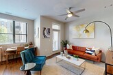 Located at 385 N Angier Ave NE in Atlanta's vibrant Old Fourth Ward neighborhood, this one-bedroom, two-bathroom residence offers a thoughtfully designed single-floor layout with modern finishes throughout. The open-concept living area features hardwood-style flooring, a ceiling fan with integrated lighting, and multiple windows that invite abundant natural light. A private door leads to a balcony, extending the living space outdoors. The kitchen is well-appointed with wood-toned cabinetry, a subway tile backsplash, stainless steel appliances including a refrigerator, electric range, dishwasher, and microwave, plus a large window overlooking the surroundings — ideal for casual dining. A clean hallway with hardwood-style flooring connects the main living areas to the private bedroom, which features plush carpeting, soft neutral walls, and a calm, restful ambiance. Both bathrooms exhibit a contemporary aesthetic with large-format tile flooring, wood-finish vanities, white countertops, and frameless glass walk-in showers with crisp tile surround. The overall design combines clean lines, neutral tones, and warm wood accents to create a cohesive, modern living environment in the heart of Atlanta.