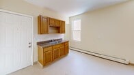 Located at 18-24 York St in Hartford, CT, this single-floor unit offers five bedrooms, one bathroom, a kitchen, and a closet within a compact yet efficiently arranged floor plan. The warm, cream-colored walls and neutral tones create a consistent and cohesive ambiance throughout the space.

The kitchen features warm-toned oak cabinetry, upper and lower storage, a double-basin sink with a dark granite-style countertop, and a window that brings in natural light. Baseboard heating runs along the wall, ensuring comfort year-round.

Each of the five bedrooms is carpeted and benefits from natural light through double-hung windows. Several bedrooms include closets with built-in rods for storage. The primary bedroom is notably spacious, offering room for generous furniture arrangements. Some bedrooms feature a curved wall detail, adding an architectural touch to the layout.

The bathroom is clean and functional, equipped with a vanity with a white basin sink, a mirror, a toilet, and a shower-tub combo. A window above the tub provides ventilation and additional natural light, while baseboard heating keeps the space comfortable.

The entry area provides a welcoming transition into the unit. Throughout the home, light-toned flooring and bright walls maintain an open, airy feel despite the efficient use of space.