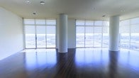 Located in the heart of Dallas, TX, this high-rise space offers an impressive blend of modern design and urban sophistication. The open floor plan is anchored by rich, dark hardwood flooring that stretches throughout, creating a warm yet refined aesthetic. A sleek cylindrical structural column serves as a defining architectural element, adding a sculptural quality to the expansive interior. Floor-to-ceiling windows wrapped in sheer roller shades line the perimeter, flooding the space with abundant natural light while framing sweeping panoramic views of the Dallas cityscape and skyline. The elevated vantage point provides an exceptional perspective of the surrounding metropolitan area, making the views a standout feature of this property. Recessed lighting in the smooth, neutral-toned ceiling complements the natural light and ensures a well-lit environment throughout the day and evening. The open layout offers remarkable flexibility, lending itself to a variety of uses — from a sophisticated residential setting to a dynamic commercial or event space. The overall ambiance is one of airy elegance, combining contemporary finishes with dramatic scale and an undeniable sense of presence above the Dallas skyline.
