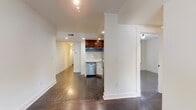 Located on Orange Street in New Haven, CT, this single-floor residence offers three bedrooms and two bathrooms with a cohesive blend of classic and contemporary design elements. Dark hardwood floors run throughout the home, providing a rich, warm foundation that contrasts with the bright white walls and crisp crown molding visible in the main living areas.

The open living space flows naturally toward the kitchen, which is defined by a structural column and features rich wood-grain upper cabinetry, light stone countertops, a tile backsplash, a stainless steel sink, and stainless steel appliances including a dishwasher and microwave. Recessed lighting keeps the kitchen well-illuminated.

The bedrooms are generously sized, each outfitted with dark hardwood floors, white walls, and closets with built-in rods for organized storage. One bedroom benefits from a large window that invites natural light and street views.

Both bathrooms share a consistent design language, featuring large-format marble-look wall tiles, mosaic tile walk-in showers with open entries, matte black fixtures and hardware, wood-toned vanities, and vessel-style sinks. The overall ambiance of the home is clean, modern, and move-in ready.