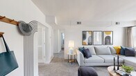 Located in Towson, MD, this 2-bedroom, 1-bathroom residence offers a well-organized single-floor layout that balances comfort and functionality. The living room serves as the heart of the home, featuring plush wall-to-wall carpeting, large windows that fill the space with natural light, and a clean white palette that creates a bright, airy atmosphere. The adjacent dining area continues the modern aesthetic, highlighted by a tray ceiling, a large window with natural light, and elegant black-framed glass panel accents that visually connect to the kitchen. The kitchen is equipped with rich cherry wood cabinetry, light stone countertops, black appliances including a range, dishwasher, and refrigerator, and warm hardwood flooring that adds a classic touch. Both bedrooms are carpeted and well-lit, with the primary bedroom offering a comfortable sense of space and a window with outdoor views. The full bathroom features white subway tile walls, a wood-toned vanity with a white countertop, and a bright window for natural ventilation. Two hallways provide seamless connectivity throughout the unit. The overall ambiance is modern and inviting, with a neutral color scheme that lends itself to a variety of interior styles.