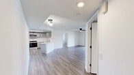 Located at 2141 Vinings Cir in Wellington, FL, this single-story, 2-bedroom, 2-bathroom home offers a well-organized layout with modern updates throughout. Light-toned luxury vinyl plank flooring runs through the main living areas and bedrooms, complementing the crisp white walls and textured ceilings fitted with ceiling fans in key rooms.

The open kitchen is a standout feature, showcasing gray shaker-style cabinetry with matte black hardware, white quartz countertops, stainless steel appliances including an electric range and built-in microwave, a deep undermount sink with a black faucet, and a skylight-style ceiling detail that adds brightness. The adjacent living room is spacious and airy, with a sliding glass door and a ceiling fan overhead.

The primary bedroom offers a comfortable footprint with a ceiling fan and natural light, while the second bedroom features a window with views of lush greenery outside. Both bathrooms are well-appointed — one includes a walk-in shower with marble-accented flooring and a window for natural light, while the other features a wide vanity with gray cabinetry, dual mirrors, and modern lighting fixtures. An attached garage provides ample storage and parking. The home's clean, neutral palette creates a move-in-ready environment throughout.
