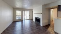 This single-floor residence offers a thoughtfully designed layout with a blend of practical features and comfortable living spaces. The open living area serves as the heart of the home, showcasing rich dark hardwood-style flooring, a textured ceiling, and a tile-surround fireplace with a clean white mantel that acts as a focal point. A sliding glass door and adjacent window flood the space with natural light and provide access to an outdoor balcony. A pendant light fixture adds a finishing touch to the adjoining dining area, which also features the same dark hardwood-style flooring.

The galley-style kitchen is efficiently designed with dark espresso cabinetry, white countertops, a stainless steel double sink, and a full suite of black appliances including a refrigerator, electric range, microwave, and dishwasher. Ample upper and lower cabinet storage lines both sides of the kitchen, maximizing functionality.

The two bedrooms are carpeted for comfort and each features a ceiling fan and windows that allow natural light to flow in. Both bathrooms are finished with dark tile tub-and-shower surrounds, white soaking tubs, hardwood-style flooring, dark vanity cabinetry, and white countertops, creating a cohesive and modern aesthetic throughout the home.
