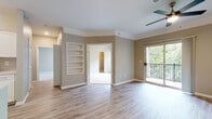 Located in Overland Park, Kansas, this single-floor residence offers a thoughtfully designed open-concept layout with a warm, neutral color palette throughout. Light hardwood-style flooring flows through the main living and kitchen areas, creating a cohesive and inviting atmosphere.

The expansive living area is highlighted by crown molding, a ceiling fan, and built-in shelving that adds both character and functionality. A sliding glass door opens to a private balcony overlooking lush greenery, allowing natural light to pour into the space.

The kitchen is well-appointed with white shaker-style cabinetry, white quartz countertops, a stainless steel sink with a modern gooseneck faucet, and a full suite of stainless steel appliances including a refrigerator, electric range, microwave, and dishwasher. A peninsula with a breakfast bar connects the kitchen seamlessly to the living area.

The primary bedroom features vaulted ceilings, a ceiling fan, plush carpeting, a walk-in closet, and a private en-suite bathroom. The en-suite offers a dual-sink vanity with white cabinetry and a full tub-shower combination. Additional bedrooms are generously sized with carpeted floors, walk-in closets, and windows that frame outdoor views. The residence combines comfort and modern finishes throughout.