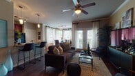 This single-story, 2-bedroom, 2-bathroom residence is thoughtfully designed to maximize comfort and functionality across a spacious layout. Dark hardwood-style flooring flows throughout the main living areas, creating a warm and cohesive aesthetic from the entry hallway through to the living room and kitchen.

The living room is a standout feature, boasting French doors that invite natural light and offer outdoor access, complemented by a bay window arrangement that further brightens the space. Crown molding and a ceiling fan add refined detail overhead. The dining area takes full advantage of a wraparound bay window configuration, flooding the space with natural light and views of surrounding greenery.

The kitchen features rich, dark cherry cabinetry paired with light countertops and black appliances, including a range, built-in microwave, dishwasher, and refrigerator. Light wood-toned flooring distinguishes this area from the rest of the home.

Both bedrooms are carpeted for comfort, each equipped with a ceiling fan and windows that allow natural light. The bathrooms include full tub-and-shower combinations with tile surrounds and tile flooring. A breakfast bar with pendant lighting connects the kitchen to the living area, enhancing the open, functional flow of the home.
