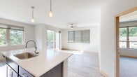 This single-floor residence is thoughtfully designed with a clean, contemporary aesthetic throughout. Light-toned luxury vinyl plank flooring flows through the main living areas, complementing the neutral palette of the walls and trim. The open-concept kitchen is a central feature, showcasing a generous island with a white quartz countertop, an undermount sink, and pendant lighting overhead. Dark-toned cabinetry with a classic shaker profile lines the walls, paired with a subway tile backsplash and a full suite of stainless steel appliances, including a range, microwave, and refrigerator. A large window above the counter fills the kitchen with natural light and views of surrounding greenery.

The living area extends from the kitchen and is bathed in natural light from a sliding glass door that opens to a private balcony overlooking mature trees. A ceiling fan adds comfort to the space. Bedrooms are carpeted and equipped with ceiling fans, offering views of the wooded surroundings through generously sized windows. The bathroom features a white vanity with a quartz countertop and a full soaking tub. A hallway closet provides additional storage, and the layout includes a walk-in closet accessible from the bathroom.