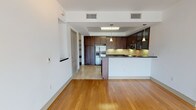 This single-floor residence offers a thoughtfully designed open-concept layout, beginning with a generous living area finished with warm hardwood flooring and track lighting overhead. The space flows seamlessly into the kitchen, which is defined by rich dark-wood cabinetry, dark granite countertops, and a full suite of stainless steel appliances, including a built-in oven, microwave, and French door refrigerator. A tile backsplash and under-cabinet lighting add refinement, while a peninsula with a white base provides a natural division between the kitchen and living areas. Pendant lights hang above the peninsula, complementing the recessed lighting in the kitchen's tray ceiling.

The bedrooms are carpeted and bright, with ceiling fans and large windows that invite natural light and views of lush palm trees. The primary bedroom connects directly to a spacious walk-in closet with built-in shelving and hanging rods, as well as a well-appointed en-suite bathroom. The bathrooms feature travertine tile flooring and wall surrounds, dark-wood vanity cabinetry, soaking tubs, and separate glass-enclosed showers, creating a clean and polished aesthetic throughout.