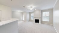Located at 401 N Old Orchard Lane in Lewisville, TX, this well-appointed one-bedroom, one-bathroom residence offers a thoughtfully designed single-floor layout with a warm, neutral color palette throughout. The open-concept living room is a standout space, featuring vaulted ceilings, crown molding, a ceiling fan, plush carpeting, and a classic fireplace framed by a clean white mantel. Large windows on either side of the fireplace flood the room with natural light, while a private exterior door provides direct outdoor access. The kitchen is efficiently laid out with a peninsula breakfast bar, white quartz countertops, light-toned cabinetry, a full suite of white appliances, and durable wood-look flooring that extends into the entry areas. The generously sized primary bedroom offers vaulted ceilings, soft carpeting, a ceiling fan, and a sliding glass door to a private balcony or patio. A walk-in closet with built-in shelving provides excellent storage, complemented by two additional closets throughout the unit. The bathroom is finished with a white vanity cabinet, white countertop, a large mirror, a multi-bulb vanity light fixture, and rich dark wood-look flooring. This residence combines comfort and functionality in a clean, move-in-ready package.