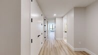 Located at 95 Wall Street in the heart of Lower Manhattan, Unit 213 is a well-appointed 550-square-foot studio apartment spanning a single floor. The unit features a thoughtfully designed open-concept layout that seamlessly integrates the living area and kitchen into one cohesive space.

The living area is finished with light-toned wood flooring throughout, crisp white walls, and clean white baseboards that lend a bright, modern aesthetic. A standout feature is the large floor-to-ceiling window, framed in dark metal, which floods the space with natural light and offers direct views of the surrounding Lower Manhattan cityscape. A built-in radiator beneath the window provides efficient heating.

The kitchen is sleek and functional, outfitted with dark wood-grain cabinetry accented by matte black hardware, white countertops, and a full suite of stainless steel appliances including a gas range, over-the-range microwave, dishwasher, and a full-size French door refrigerator. Subtle under-cabinet lighting adds a warm, modern touch. The floorplan also reveals a dedicated bathroom and closet space, maximizing utility within the compact footprint. Overall, the unit offers a clean, contemporary living environment ideal for urban living.