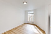 Located at 1030 Post St in San Francisco's Lower Nob Hill neighborhood, this one-bedroom, one-bathroom unit offers a clean and functional layout across a single floor. The interior is defined by a crisp, all-white color palette and light hardwood flooring that runs through the main living areas, hallway, and kitchen, creating a bright and cohesive aesthetic throughout.

The bedroom features soft carpeted flooring and a window with views of the surrounding neighborhood, fitted with a baseboard heater beneath. Ample wall space provides flexibility for furniture arrangement. A second room, also carpeted and accessed via the hallway, offers additional versatile space. The narrow hallway, lined with textured white walls and the same light hardwood flooring, connects the rooms efficiently.

The kitchen is compact and practical, featuring white cabinetry and a full-size refrigerator. The bathroom includes standard fixtures with clean white finishes and brushed nickel hardware accents. Natural light filters in through windows in the bedroom areas, lending warmth to the otherwise neutral interior. The overall ambiance is minimal and move-in ready, well-suited for those seeking a straightforward, low-maintenance living space in the heart of San Francisco.