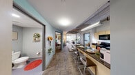 Located in the heart of downtown Ann Arbor, this three-bedroom, two-bathroom residence offers a compelling blend of modern urban design and functional living. The unit showcases an industrial-inspired aesthetic throughout, with exposed concrete ceilings, visible ductwork and piping, and large windows that flood each room with natural light and frame impressive views of the Ann Arbor skyline and surrounding cityscape.

The living area is anchored by expansive floor-to-ceiling corner windows, creating a bright, open atmosphere with panoramic city views that make it a natural focal point of the home. The galley-style kitchen features light wood cabinetry, dark stone countertops, and rich hardwood flooring, offering a well-equipped and efficient cooking space.

Each of the three bedrooms carries the industrial character of the unit, with exposed ceiling elements and generous windows overlooking the city. The primary bedroom provides a comfortable retreat with ample room for a study area. The two bathrooms are clean and functional — one features a walk-in shower with contemporary finishes, while the second offers a pedestal sink and shower combination. Throughout the unit, the elevated floor position enhances the sense of openness and delivers striking urban vistas from virtually every room.