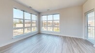 Located at 7730 Harkins Rd in Lanham, MD, this well-appointed 2-bedroom, 2-bathroom residence offers a thoughtfully designed single-floor layout. The open-concept kitchen and living area serves as the heart of the home, featuring light wood-style flooring, recessed lighting, and large windows that invite abundant natural light and outdoor views. The kitchen is equipped with stainless steel appliances — including a refrigerator, range, and over-the-range microwave — complemented by white cabinetry extending to the ceiling, granite countertops, and a central island with a sink, ideal for both cooking and entertaining. The living area connects seamlessly to one of two private balconies, extending the living space outdoors. Both bedrooms are carpeted and well-sized, with the primary bedroom offering generous proportions and ample closet space. The second bedroom features a large window with open views of the surrounding area. Each bathroom is finished with granite-topped vanities, illuminated mirrors, and wood-style flooring. Additional conveniences include in-unit laundry, four closets for storage, and a connecting hallway that ties the layout together efficiently. The clean, neutral palette throughout creates a bright and modern ambiance.
