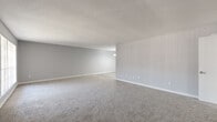 Located at 10500 Valley Forge Dr in Houston, Texas, this single-floor unit offers a clean, neutral aesthetic throughout, with light gray walls and white trim creating a bright, cohesive feel. The expansive living area features plush carpeting, a textured ceiling, and a vertical-panel accent wall, offering generous open space ideal for a variety of furniture arrangements. Natural light filters in through large windows fitted with vertical blinds, enhancing the airy atmosphere. The kitchen is outfitted with white cabinetry, light granite-style countertops, wood-look luxury vinyl plank flooring, and black appliances including a refrigerator, range, and microwave — all complemented by a window that brings in additional natural light. The bedrooms are well-proportioned, each featuring soft carpeting and ceiling fans with integrated lighting. The primary bedroom stands out with two walk-in closets and its own window, while additional bedrooms offer walk-in closet access and ceiling fans as well. A versatile flex space with wood-look flooring and a pendant light provides options for use as a dining area or home office. Throughout the unit, clean finishes, ample storage, and a thoughtful layout contribute to a practical and comfortable living environment.