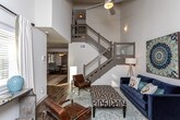 This two-floor Atlanta residence offers a thoughtfully designed layout with a blend of modern finishes and comfortable living spaces. The living room serves as a focal point, featuring soaring vaulted ceilings that enhance the sense of openness, hardwood-style flooring, and a striking stone-surround fireplace with a sleek mantle. Natural light filters through the space, complementing the bright, neutral walls throughout.

The kitchen is well-equipped with gray shaker-style cabinetry extending to the ceiling, granite countertops, a textured tile backsplash, and a full suite of stainless steel appliances including a gas range, built-in microwave, dishwasher, and refrigerator. Under-cabinet lighting adds both function and ambiance.

The bedrooms are carpeted and generously proportioned. The primary bedroom benefits from notably high ceilings and direct access to an en-suite bathroom, while a secondary bedroom features a large window with outdoor views. The bathrooms are finished with granite-topped vanities, gray cabinetry, wood-look tile flooring, and glass-enclosed shower-tub combinations, delivering a clean, contemporary aesthetic throughout.