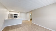 Located at 2350 Cypress Pond Road in Palm Harbor, Florida, this one-bedroom, one-bathroom unit offers a practical and efficiently designed single-floor layout. The open-concept kitchen and living area anchors the space, featuring light wood-style flooring that flows throughout the unit, creating a cohesive and clean aesthetic. The kitchen is equipped with white shaker-style cabinetry with brushed nickel hardware, white quartz countertops, a single-basin undermount sink, and stainless steel appliances including a refrigerator, range, and over-the-range microwave. A peninsula counter provides additional workspace and a natural division between the kitchen and living area. The bedroom offers a comfortable footprint with a ceiling fan, a window with blinds that allows natural light and outdoor views, and access to a dedicated closet. The full bathroom is finished with a white vanity with quartz countertop, a tiled tub-shower combination featuring marble-style wall tile, and light wood-style flooring that coordinates with the rest of the unit. Neutral warm-gray wall tones and textured ceilings are consistent throughout, contributing to a clean, move-in-ready atmosphere.