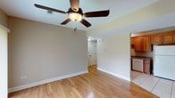 This single-floor, two-bedroom, two-bathroom residence offers a practical and comfortable layout with consistent design elements throughout. The open living area features warm hardwood-style flooring, neutral beige walls, and a ceiling fan with a light fixture, creating a bright and airy atmosphere. A sliding glass door floods the space with natural light and provides outdoor access. The living area flows seamlessly into the kitchen, which is outfitted with rich wood cabinetry, granite-style countertops, tile flooring, and a full suite of white appliances including a refrigerator, range, microwave, and dishwasher.

Both bedrooms are generously proportioned, finished with plush carpeting, ceiling fans, and neutral-toned walls. One bedroom includes a window with natural light, while the other connects directly to a full bathroom. The two bathrooms are well-appointed, each featuring a tub-shower combination with white surround, tile flooring, and vanities with granite-style countertops and wood cabinetry. The overall design maintains a cohesive, neutral palette throughout, offering a clean and functional living environment.